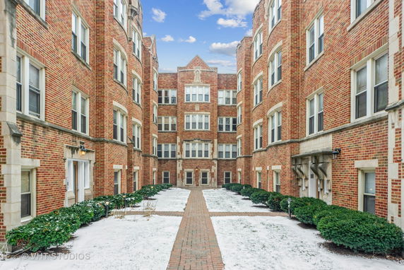 Front view of a multi-story brick apartment building with a courtyard.