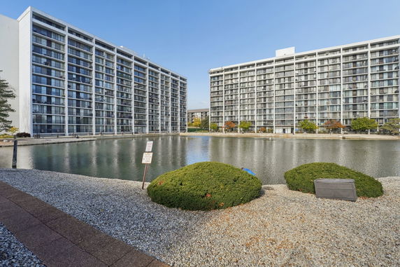 View of two tall apartment buildings next to a body of water.