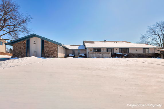 Front view of a single-story house with a brick facade and snow-covered front yard.