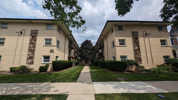 Front view of a brick apartment building with multiple floors and balconies.