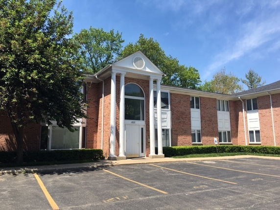 Front view of a two-story brick building with a central entrance and columns.