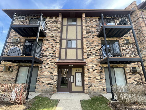 Front view of a multi-story brick apartment building with balconies.