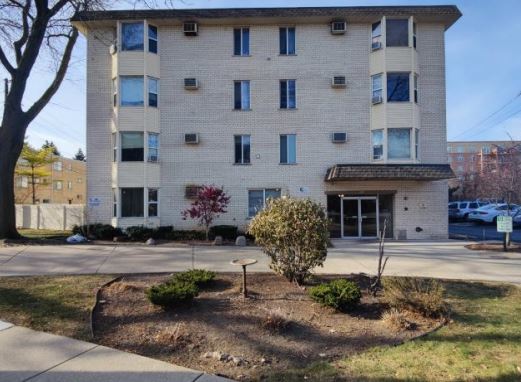 Front view of a multi-story residential building with windows and a small entrance canopy.