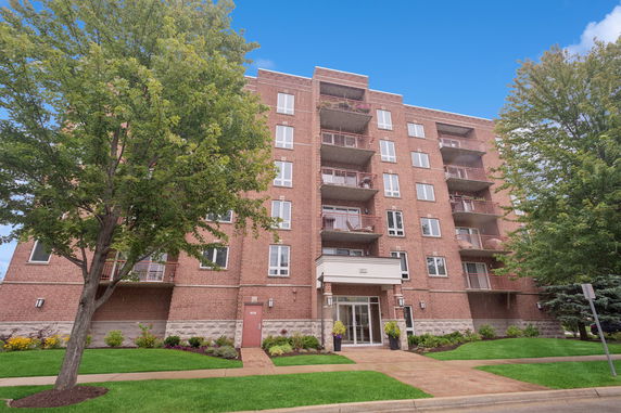 Front view of a multi-story brick apartment building with balconies.