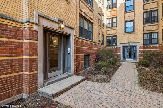 Front view of a brick multi-story building with entrance doors and windows.