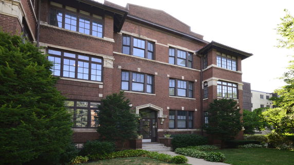 Front view of a multi-story brick building with large windows.
