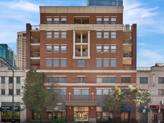 Front view of a multi-story brick building with balconies and commercial spaces on the ground floor.