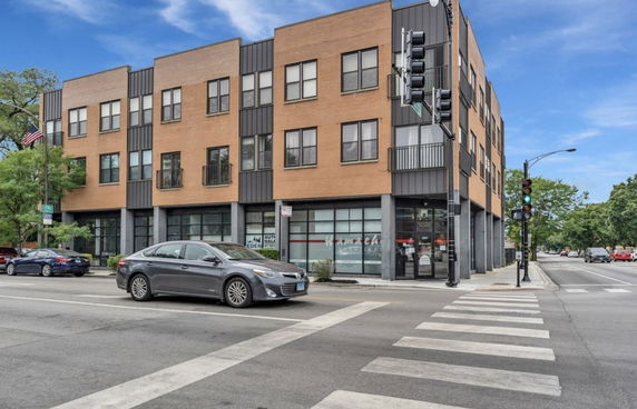 Front view of a multi-story commercial and residential building on a street corner.