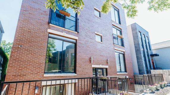 Front view of a multi-story brick building with large windows.