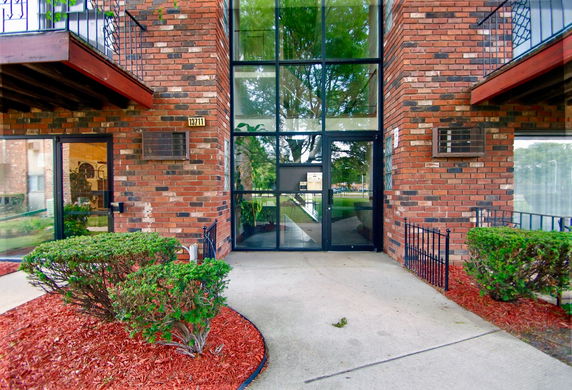 Front view of a brick building with large glass entryway and balconies.