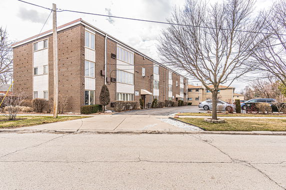 Front view of a multi-story brick apartment building with large windows.