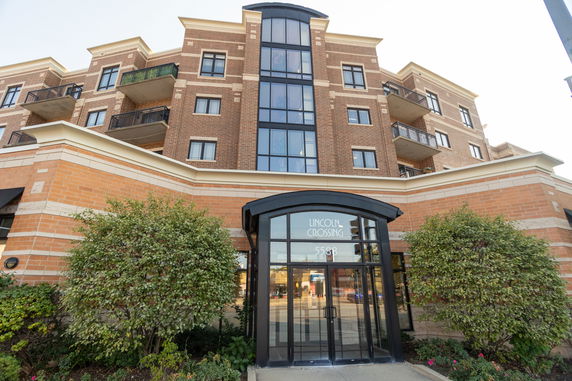 Front view of a multi-story building with balconies and a central glass entrance.