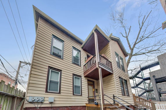 Front view of a two-story house with stairs leading to the entrance