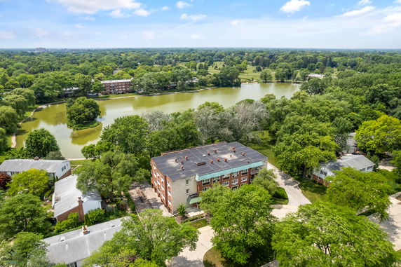 Aerial view of a residential area with a body of water and surrounding greenery.