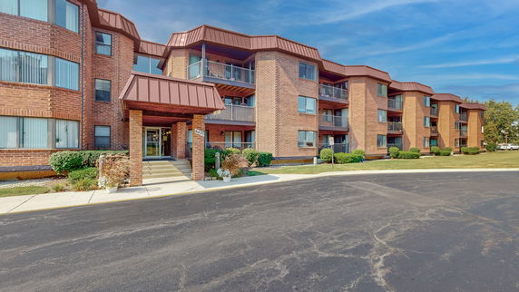 Front view of a multi-story brick apartment building with balconies.