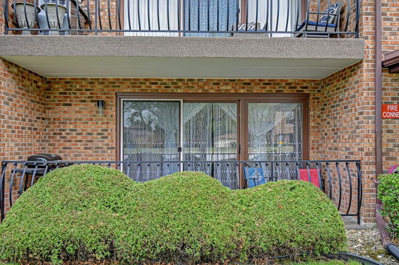 Front view of a brick building with a balcony and glass sliding doors.