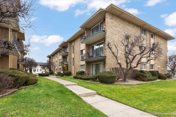 Front view of a multi-story apartment building with balconies and brick exterior.
