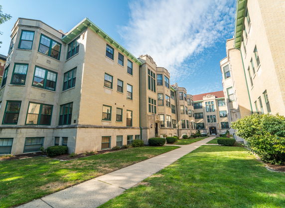 Front view of a multi-story apartment building with large windows.