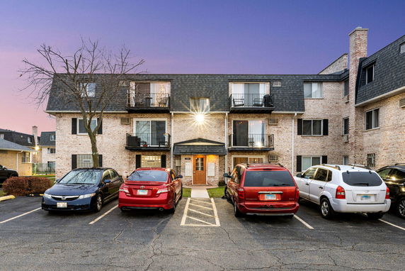 Front view of a multi-story residential building with balconies and parking area.