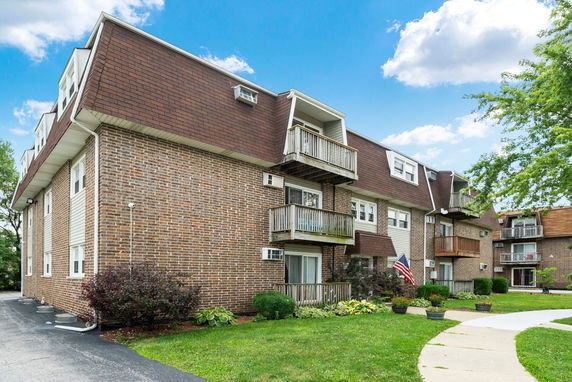 Front view of a multi-story brick apartment building with balconies.