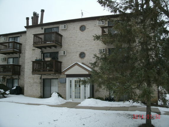 Front view of a multi-story apartment building with balconies and brick exterior.