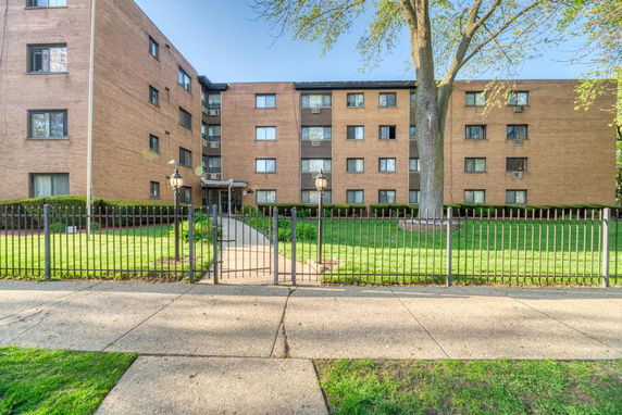 Front view of a multi-story apartment building with a gated entrance.