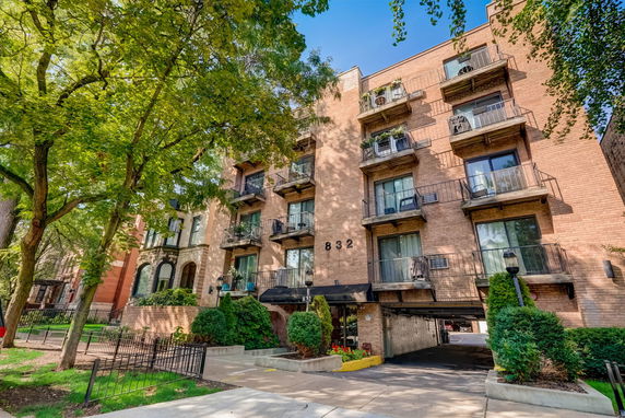 Front view of a multi-story residential building with balconies and a driveway.