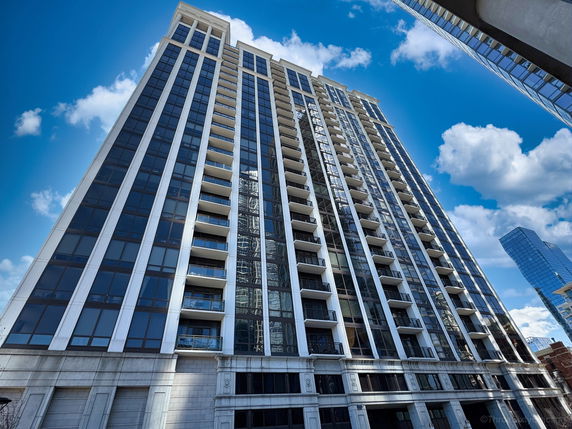 Front view of a high-rise residential building with balconies and large windows.