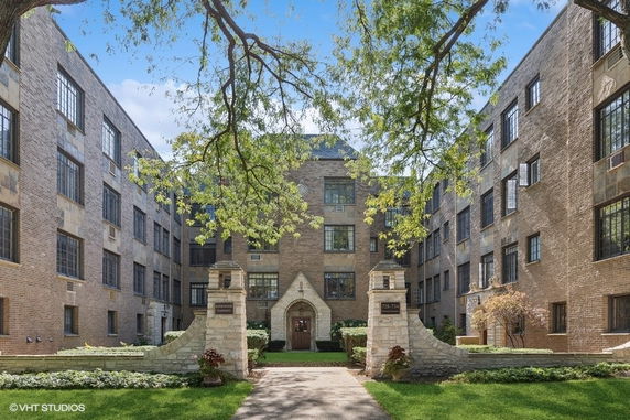 Front view of a multi-story brick apartment building with a central arched entrance.