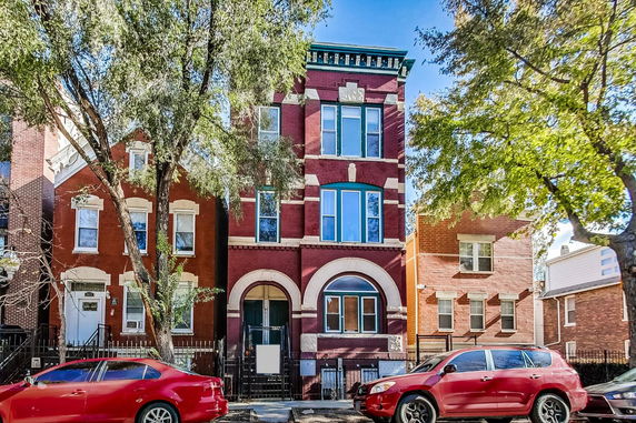 Front view of a three-story brick building with arched windows and entry.