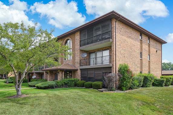 Front view of a multi-story brick apartment building with balconies.