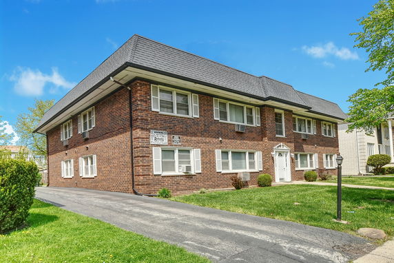 Front view of a two-story brick building with multiple windows and a sloped roof.