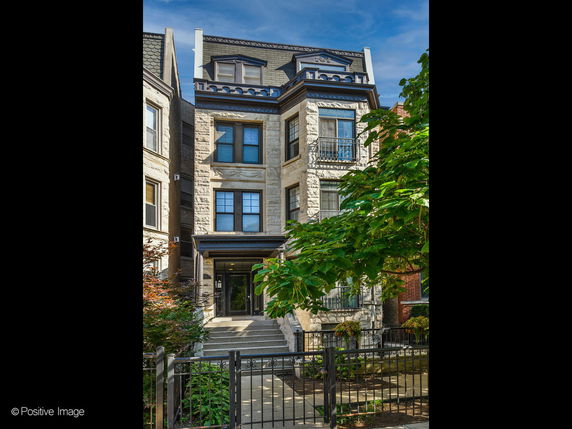 Front view of a multi-story residential building with a stone facade and decorative architectural details.