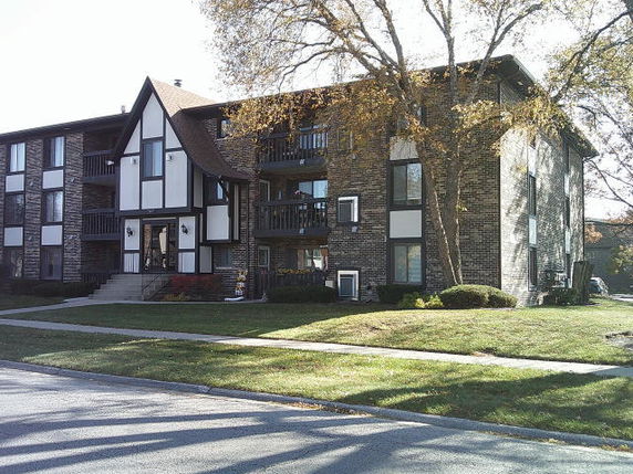 Front view of a multi-story apartment building with brick facade and balconies.