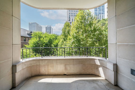 Panoramic view from a balcony overlooking trees and city buildings.
