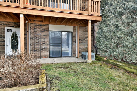 Front view of a house with a wooden balcony and a sliding glass door.