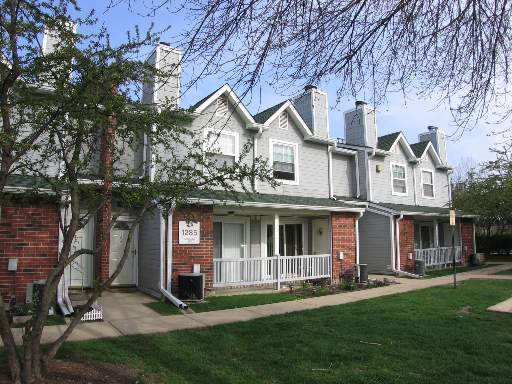 Front view of a two-story townhouse with a porch and chimneys.