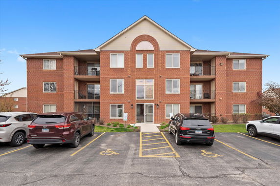 Front view of a three-story brick apartment building with balconies.