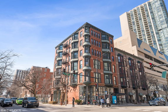 Front view of a multi-story brick building on a street corner.
