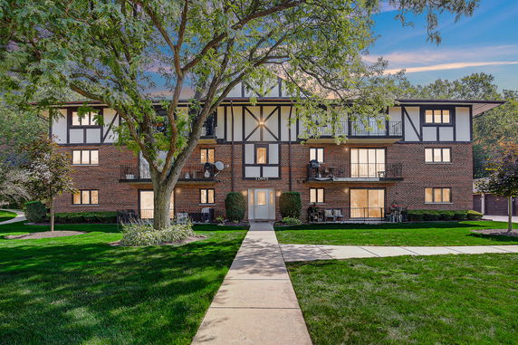 Front view of a three-story apartment building with a brick exterior and balconies.