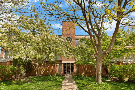 Front view of a building with brick facade and large trees in front.