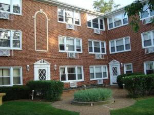 Front view of a brick apartment building with multiple windows and entryways.