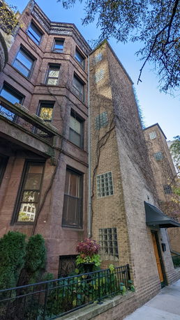 Front view of a multi-story building with a brick facade and vine-covered walls.