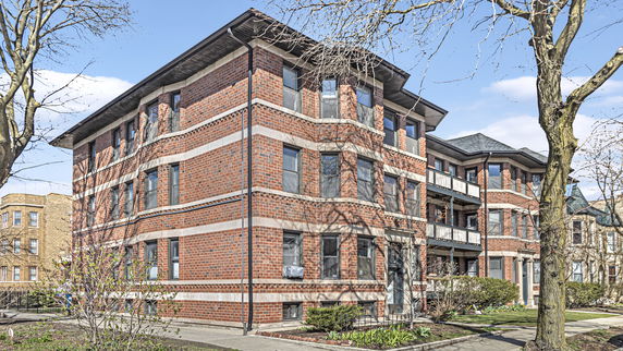 Front view of a multi-story brick building with a balcony.
