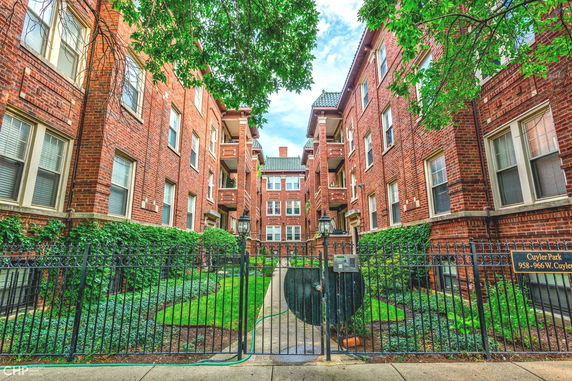 Front view of a brick apartment building with a central entry gate and garden.