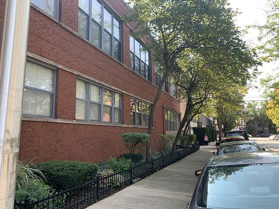 Side view of a multi-story brick building with large windows.