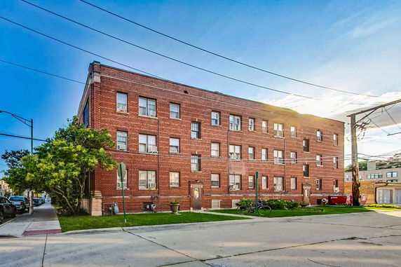 Front view of a multi-story red brick building with multiple windows.