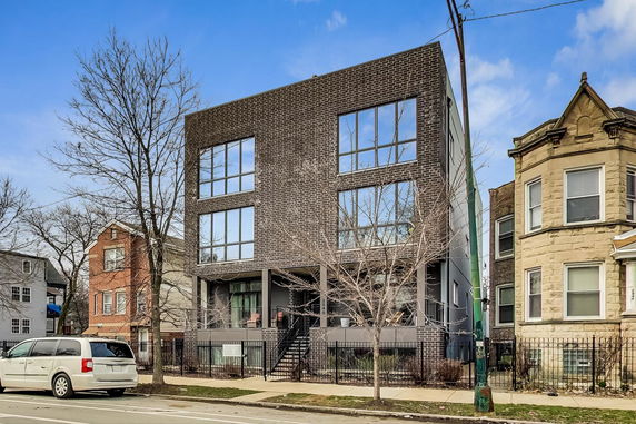 Front view of a modern three-story brick building with large windows.