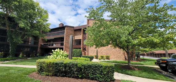 Front view of a multi-story brick apartment building with balconies.