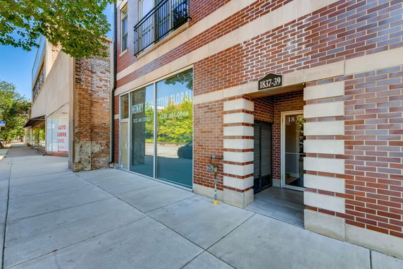 Front view of a brick building with large glass storefront windows.